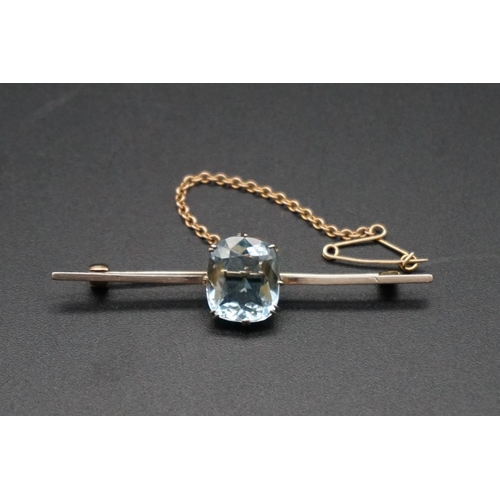 717 - A yellow metal aquamarine bar brooch, stamped 15, the cushion stone approximately 5.6ct, 61mm gross ... 