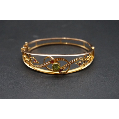 721 - Suffragette Interest: an Edwardian yellow metal hinged bangle, set with peridot, pearls & rubies... 