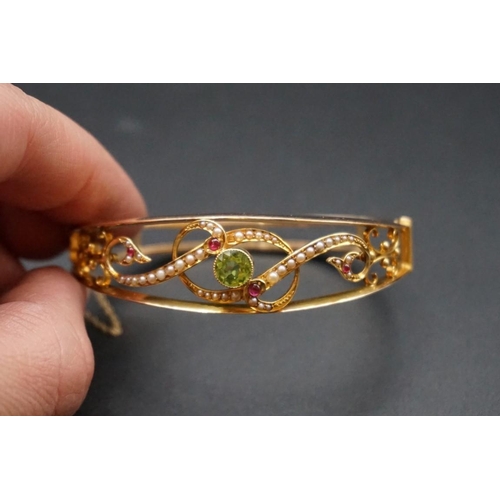 721 - Suffragette Interest: an Edwardian yellow metal hinged bangle, set with peridot, pearls & rubies... 