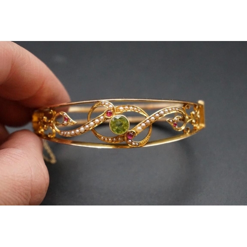 721 - Suffragette Interest: an Edwardian yellow metal hinged bangle, set with peridot, pearls & rubies... 