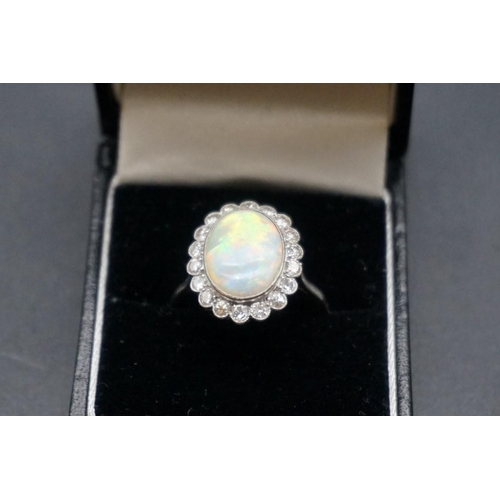 735 - An opal and diamond cluster ring, stamped 'plat', with eighteen collet set diamonds, size T1/2.... 