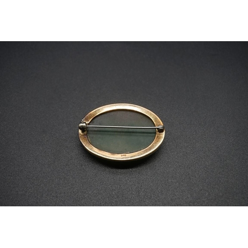 744 - A yellow metal oval moss agate brooch, the mount stamped 9ct, 36mm