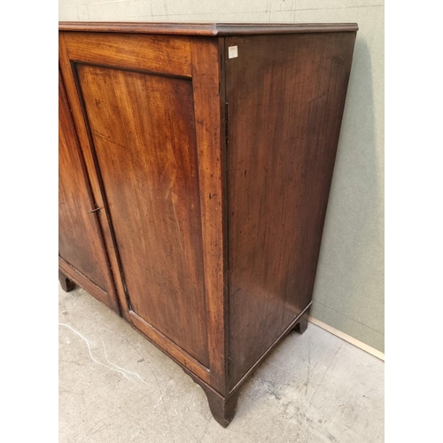 1083 - An unusual George III mahogany press cupboard, the pair of panel doors enclosing a frieze drawer and... 