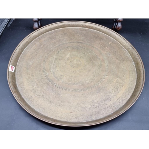 1098 - A brass circular tray on folding stand, decorated with Egyptian figures and Arabic inscription, 57cm... 