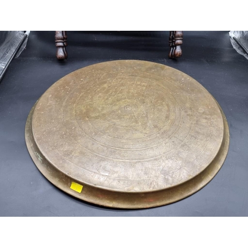 1098 - A brass circular tray on folding stand, decorated with Egyptian figures and Arabic inscription, 57cm... 