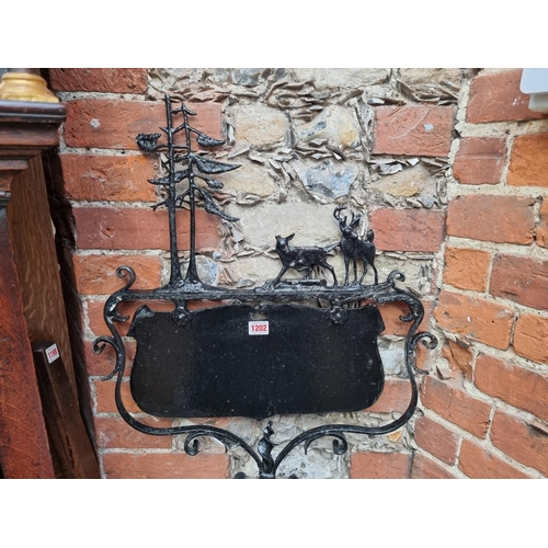 1202 - A black painted wrought iron sign, total height 146cm.