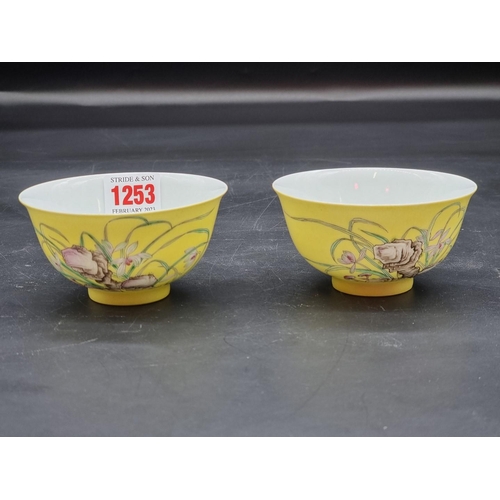 1253 - A pair of Chinese yellow ground bowls, 20th century, painted with flowers and inscribed with columns... 