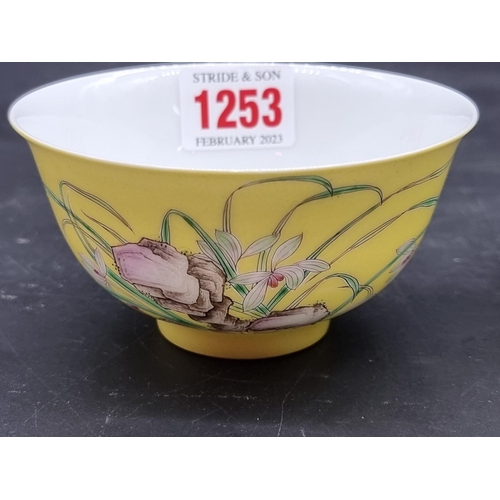 1253 - A pair of Chinese yellow ground bowls, 20th century, painted with flowers and inscribed with columns... 