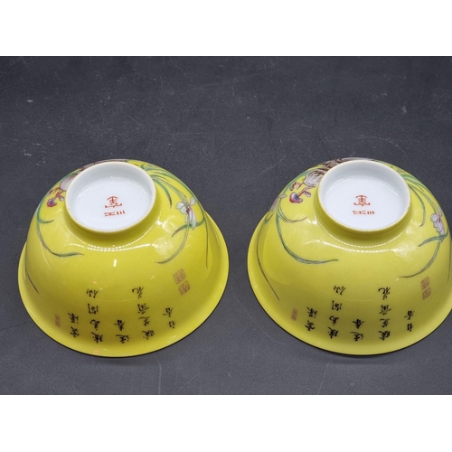 1253 - A pair of Chinese yellow ground bowls, 20th century, painted with flowers and inscribed with columns... 