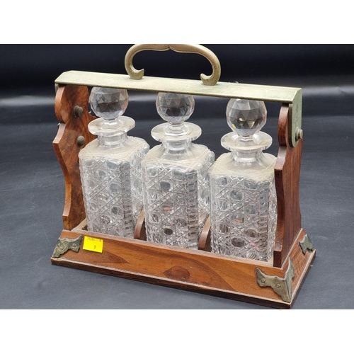 1393 - A walnut and electroplate three bottle tantalus, by Betjemann, 31cm wide, (chips to collars of two d... 