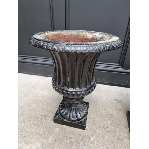 1204 - A pair of black painted cast iron Campana urns and stands, 69cm high.