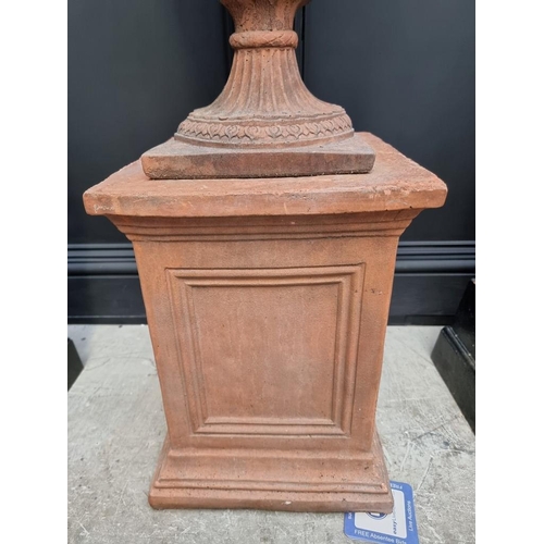 1207 - A large red composition stone twin handled urn, 84cm high, on associated pedestal, total height 132c... 