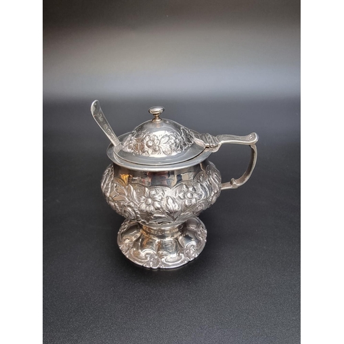 301 - An antique silver mustard pot, having later floral embossed decoration, 9.5cm high; together with a ... 