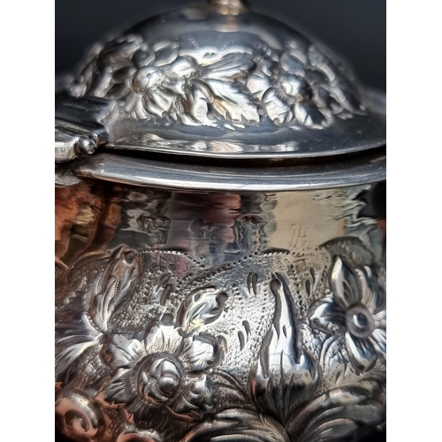 301 - An antique silver mustard pot, having later floral embossed decoration, 9.5cm high; together with a ... 