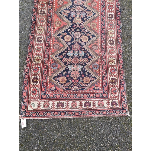 1016 - A Persian runner, having central diamond with floral and geometric design, with floral borders on a ... 