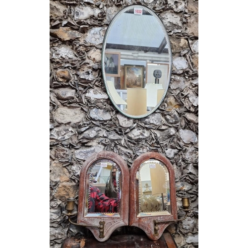 1032 - A 1920s oval wall mirror, 43 x 28cm; together with a small pair of oak framed girandoles, 32.5cm hig... 