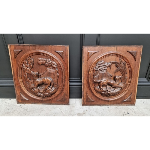 1056 - A pair of relief carved oak panels, each decorated with a dog, 51 x 47cm.