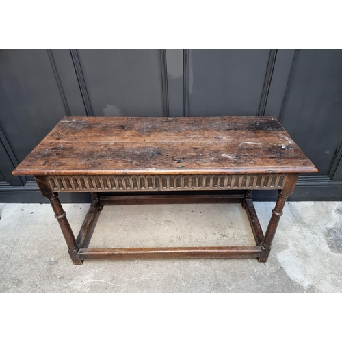 1063 - A late 17th century oak rectangular table, with carved frieze to one long side and peripheral stretc... 