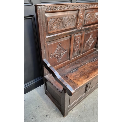 1086 - An antique carved oak box seat settle, 136cm wide.