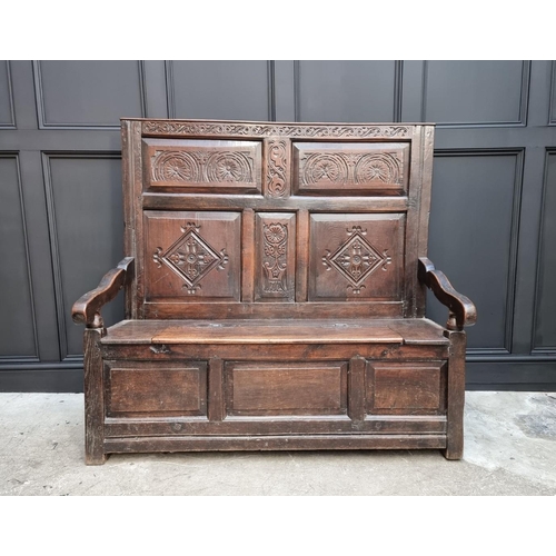 1086 - An antique carved oak box seat settle, 136cm wide.