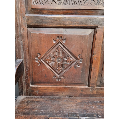 1086 - An antique carved oak box seat settle, 136cm wide.