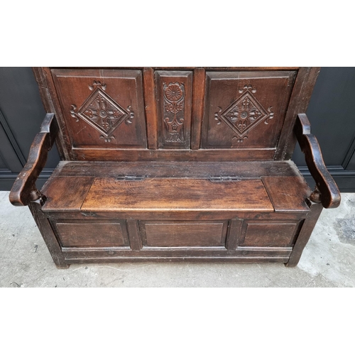 1086 - An antique carved oak box seat settle, 136cm wide.