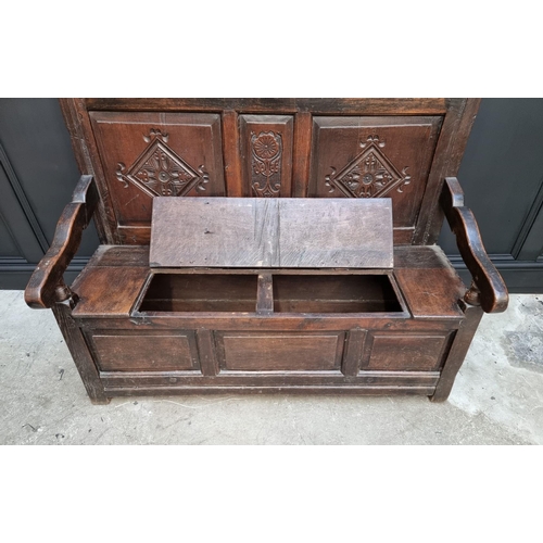 1086 - An antique carved oak box seat settle, 136cm wide.