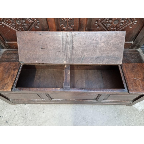 1086 - An antique carved oak box seat settle, 136cm wide.