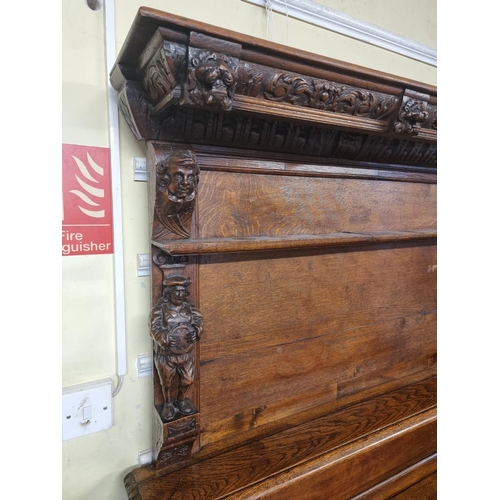 1128 - A Victorian carved oak dresser and rack, incorporating caryatid figures and panels of tavern scenes,... 