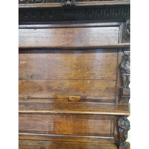 1128 - A Victorian carved oak dresser and rack, incorporating caryatid figures and panels of tavern scenes,... 