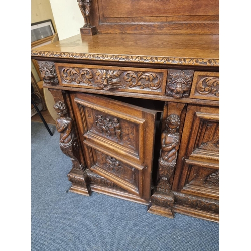 1128 - A Victorian carved oak dresser and rack, incorporating caryatid figures and panels of tavern scenes,... 