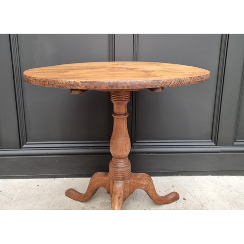 1160 - A George III elm circular tilt top tripod table, with one piece top, 63cm diameter, (one leg a.f.); ... 