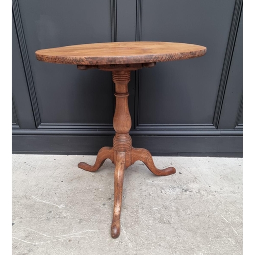 1160 - A George III elm circular tilt top tripod table, with one piece top, 63cm diameter, (one leg a.f.); ... 