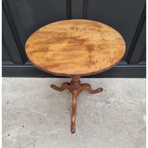 1160 - A George III elm circular tilt top tripod table, with one piece top, 63cm diameter, (one leg a.f.); ... 