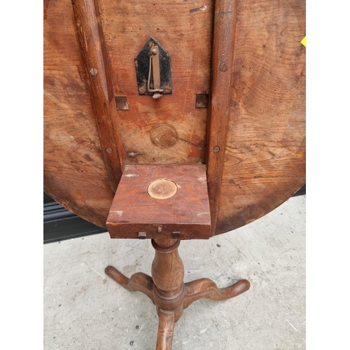 1160 - A George III elm circular tilt top tripod table, with one piece top, 63cm diameter, (one leg a.f.); ... 