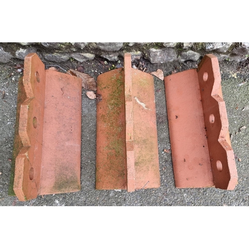 1676 - Three large decorative composition red stone roof tile ridges, 45cm wide.