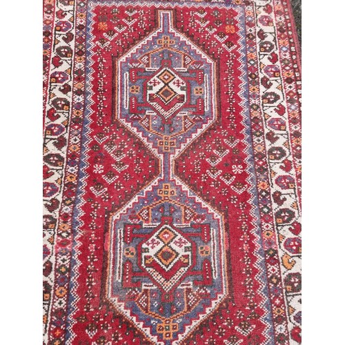 1004 - A Persian rug, having two medallions, with floral borders, 160 x 105cm.