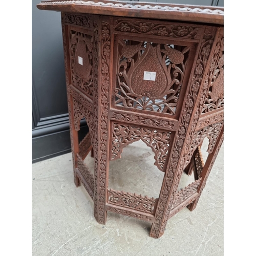 1035 - An Indian carved and pierced hardwood octagonal folding table, 61cm wide. 