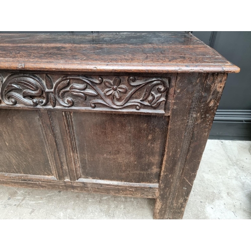 1053 - A 17th century oak panelled coffer, with unusual carved frieze, 138cm wide. 