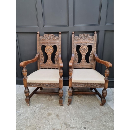 1017 - A pair of late Victorian carved oak open armchairs, with studded cream leather seats.... 