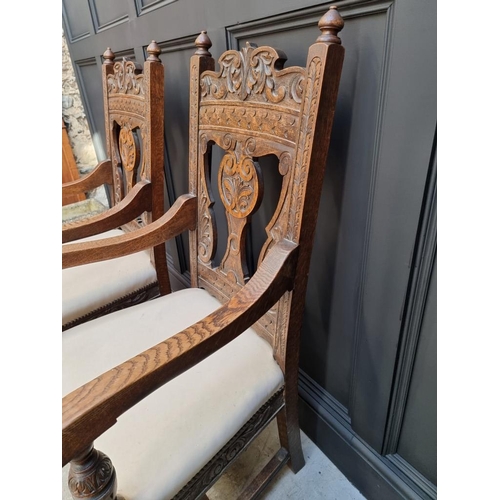 1017 - A pair of late Victorian carved oak open armchairs, with studded cream leather seats.... 