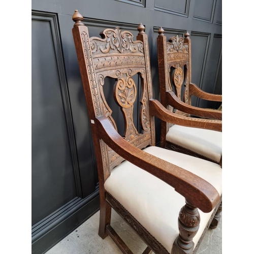 1017 - A pair of late Victorian carved oak open armchairs, with studded cream leather seats.... 