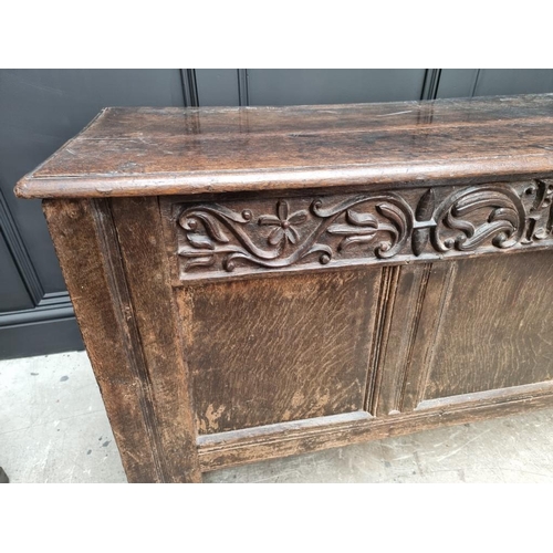 1053 - A 17th century oak panelled coffer, with unusual carved frieze, 138cm wide. 