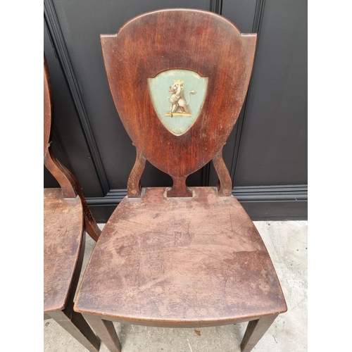 1075 - An interesting set of three George III shield back hall chairs, each with painted lion crest to back... 