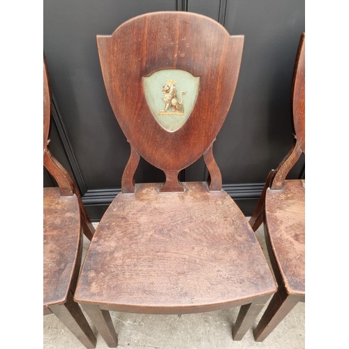 1075 - An interesting set of three George III shield back hall chairs, each with painted lion crest to back... 