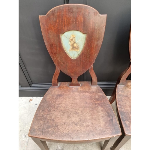 1075 - An interesting set of three George III shield back hall chairs, each with painted lion crest to back... 