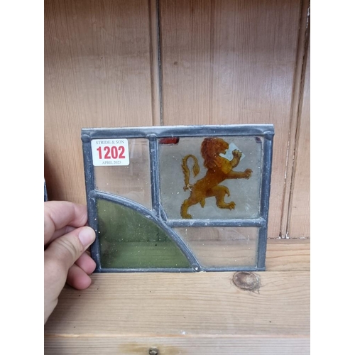 1202 - Three old stained and leaded glass panels, largest 38 x 23cm; together with an acrylic advertising s... 