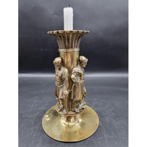 1454 - A brass candlestick, moulded with three Roman centurions, 25cm high.