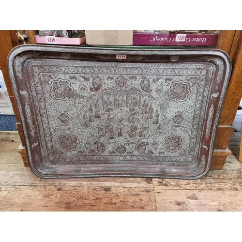 1712 - A large Persian or Indian copper rectangular tray, engraved with stylized figures and with a line of... 