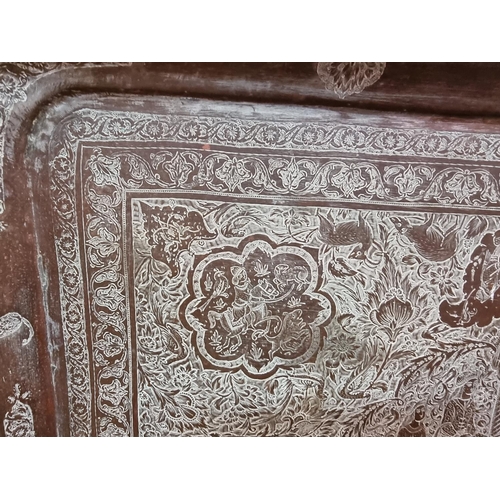 1712 - A large Persian or Indian copper rectangular tray, engraved with stylized figures and with a line of... 